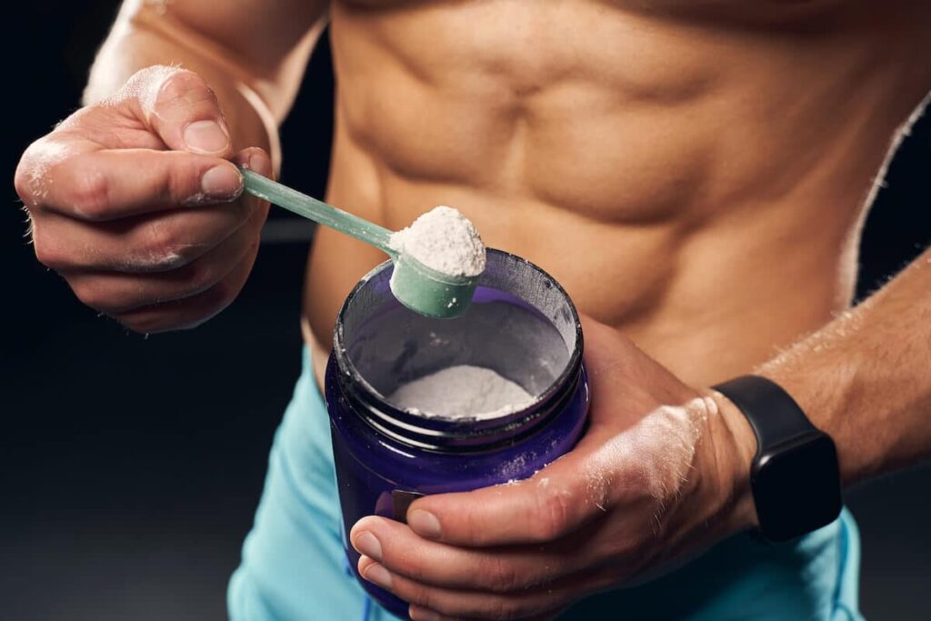 An Athletic man holding a scoop of powdered supplement